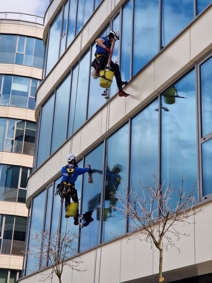 project-01-b Deux laveurs de vitres suspendus par cordes sur un gratte-ciel moderne, mettant en scène une maintenance professionnelle en milieu urbain.