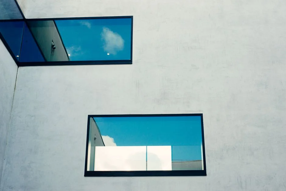 Des laveurs de vitres en hauteur, équipés de protections, nettoient la façade d’un gratte-ciel.